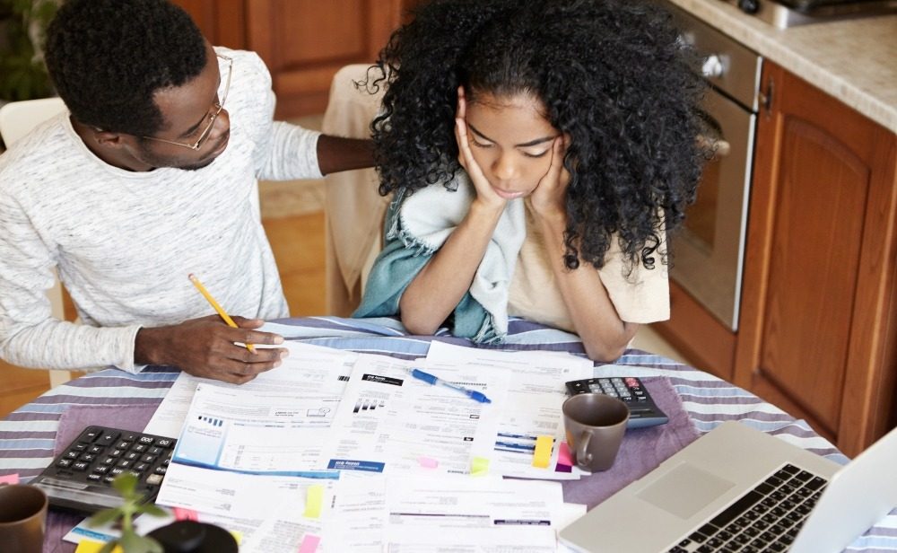 Two people going through financial papers and a calculator at a table